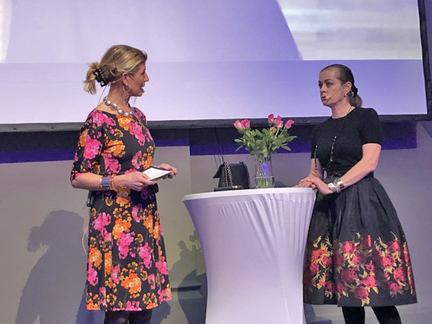 Moderator Pernilla Warberg på scen i samtal med kvinna