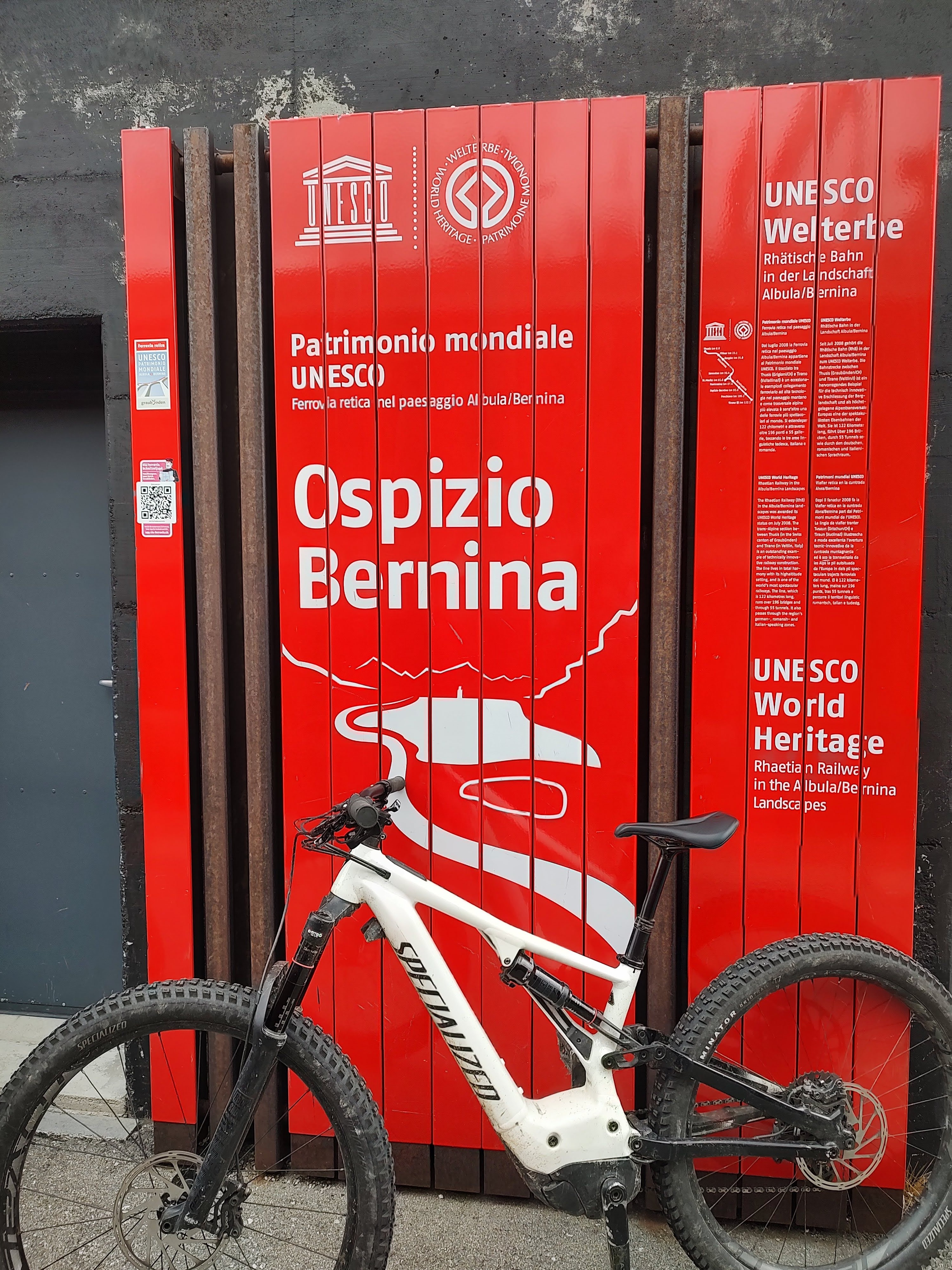 Cykel lutad mot skylt på Passet bernina i Schweiz