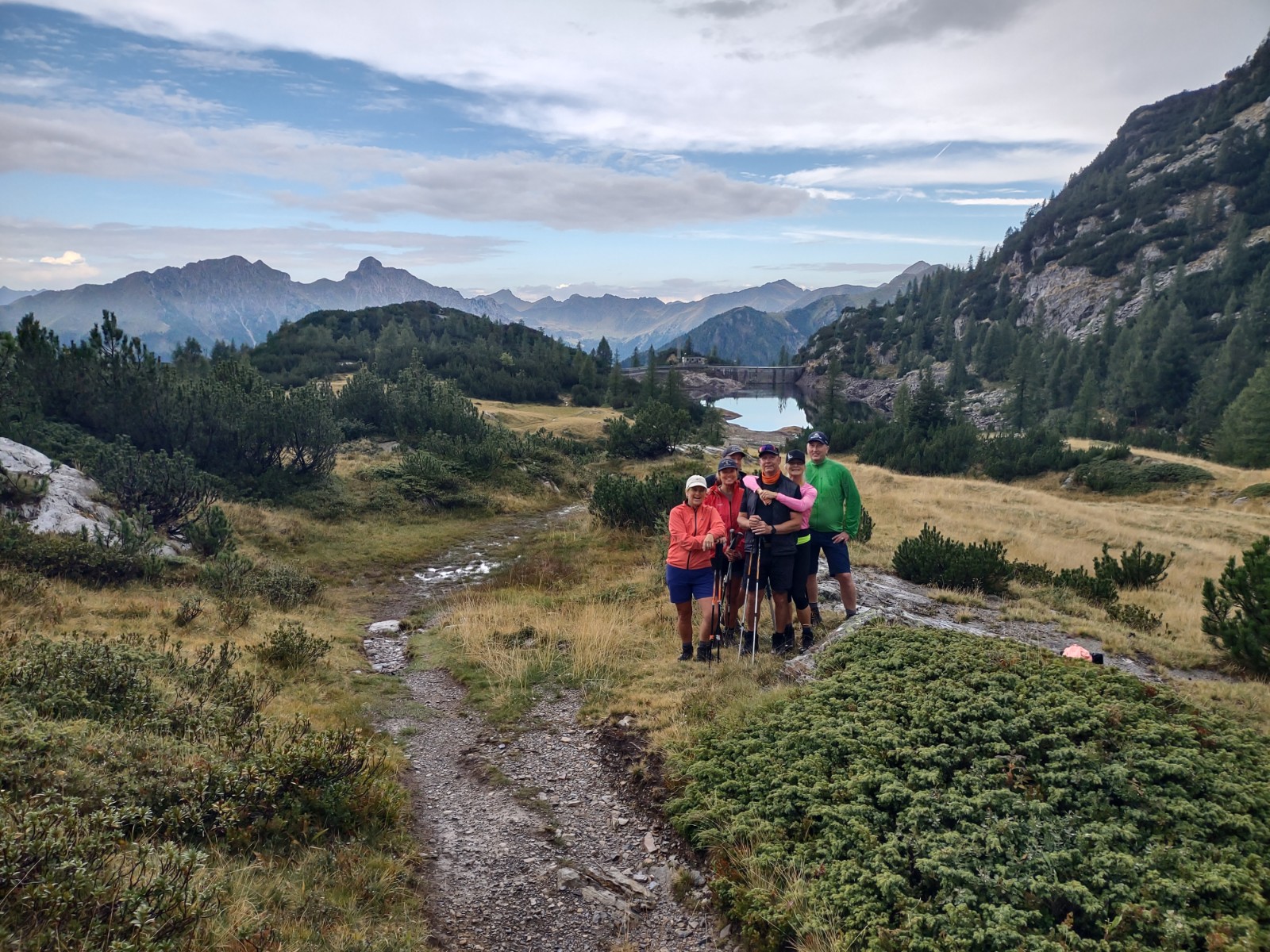 Liten grupp i vandringskläder med stavar på utsiktsplats i bergen