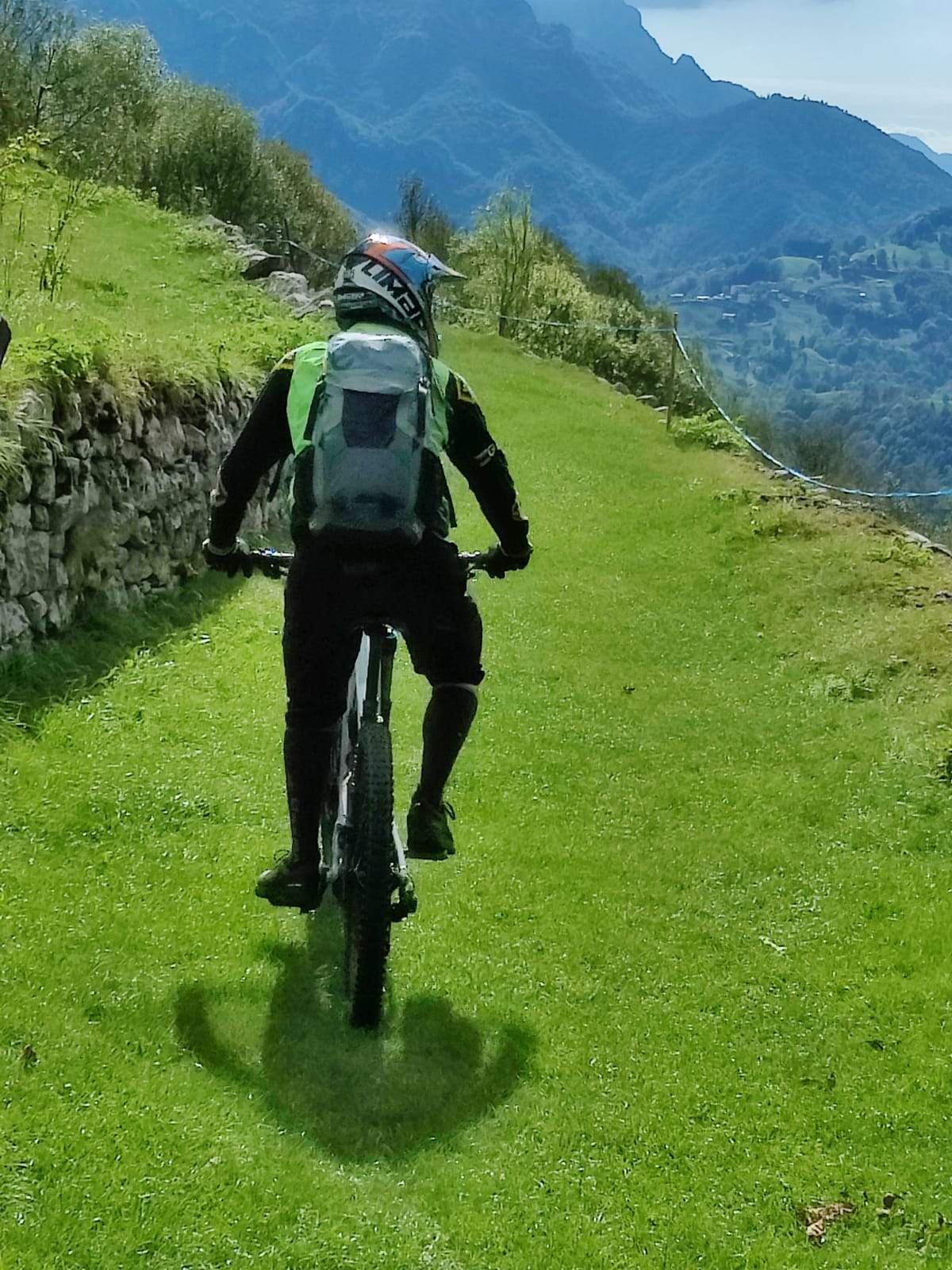 cyklist med integralhjälm och skyddsryggsäck cyklar på en gräsbeklädd stig