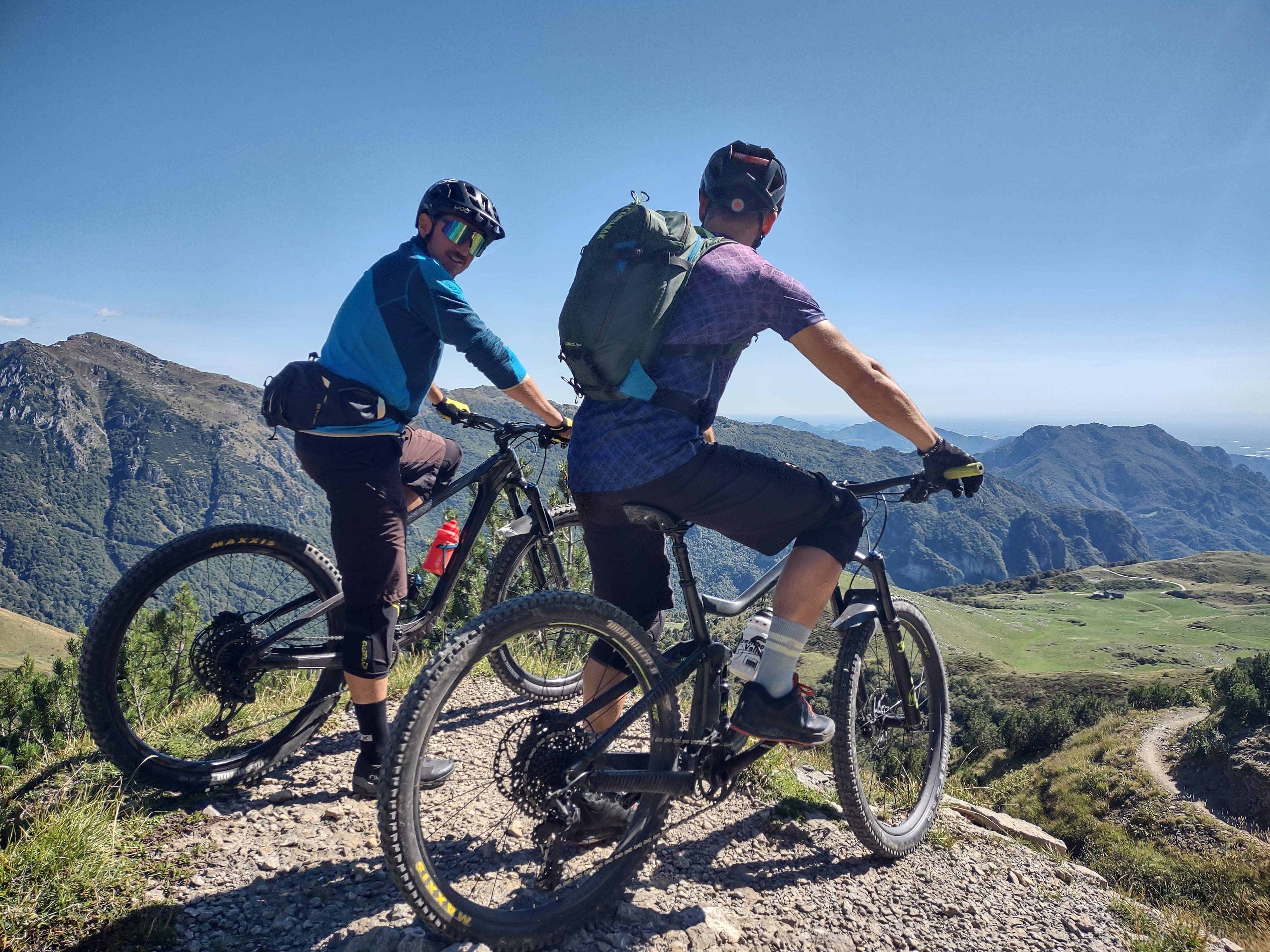 Två mountainbikecyklister med hjälm och ryggsäck tittar ut över dalgången
