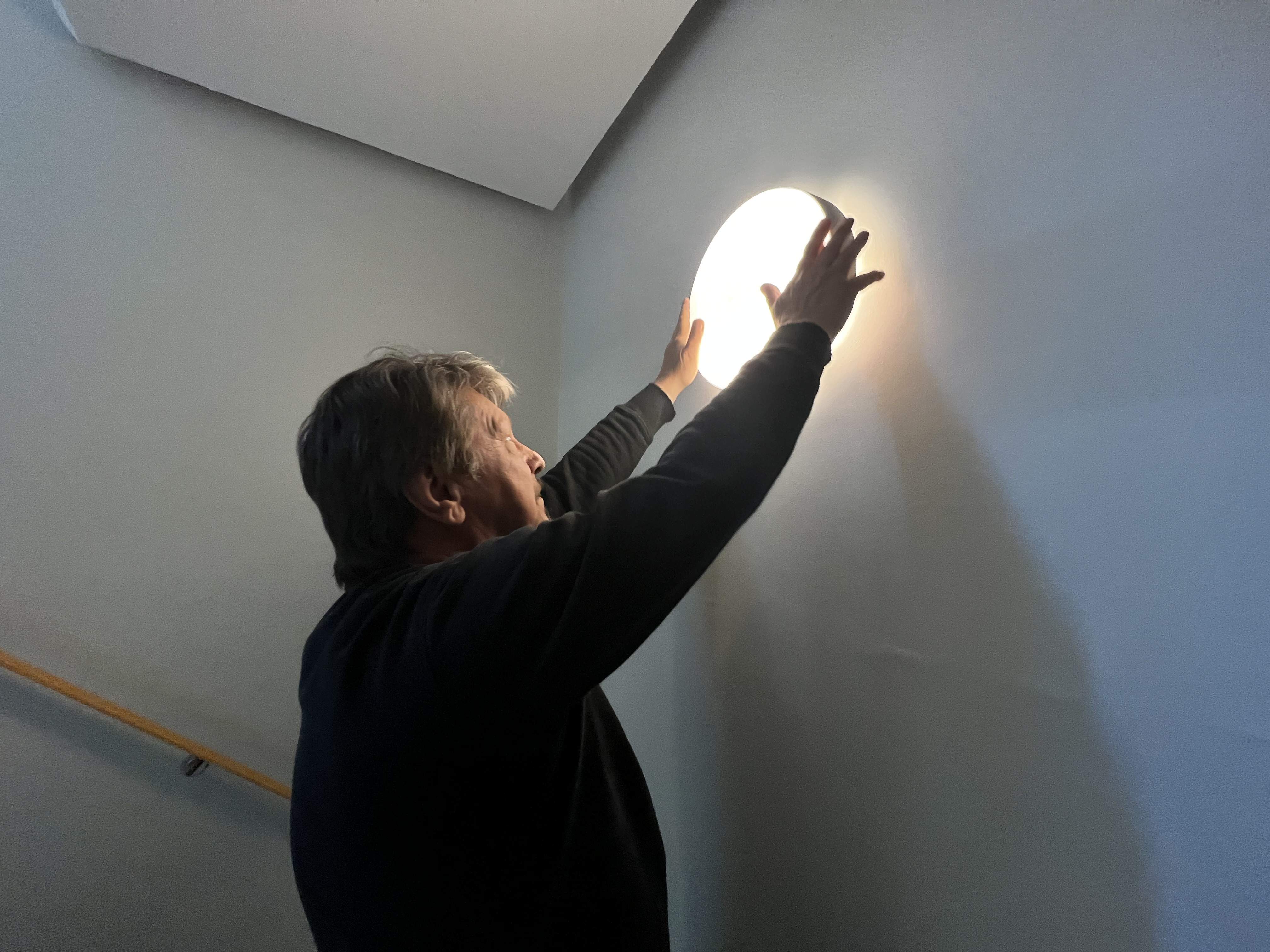 En tekniker som utför fastighetsservice där han byter ut en lampa i lägenhetsbyggnadens hall