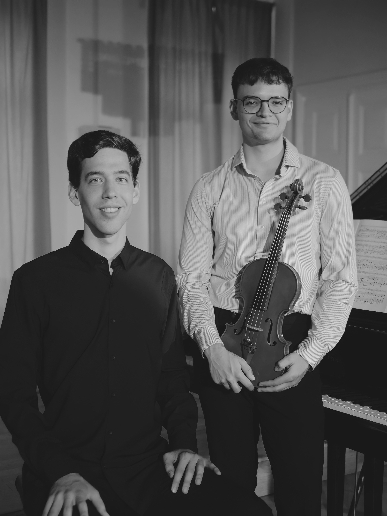 Svartvitt foto på András Moldoványi och Andreas Siles-mellinger. Andreas håller i sin violin. Bredvid står en flygel.