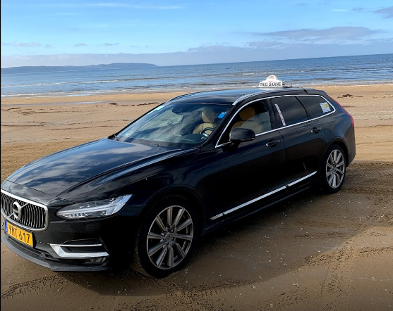 A Volvo during the day parked near the beach