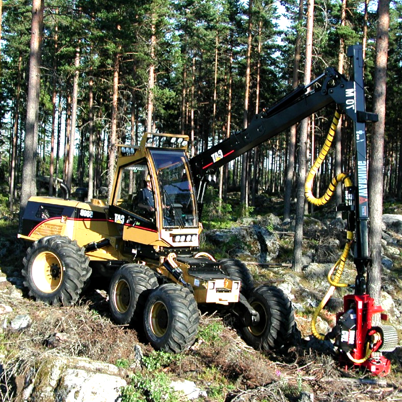 En gul skördemaskin som arbetar i skogen.