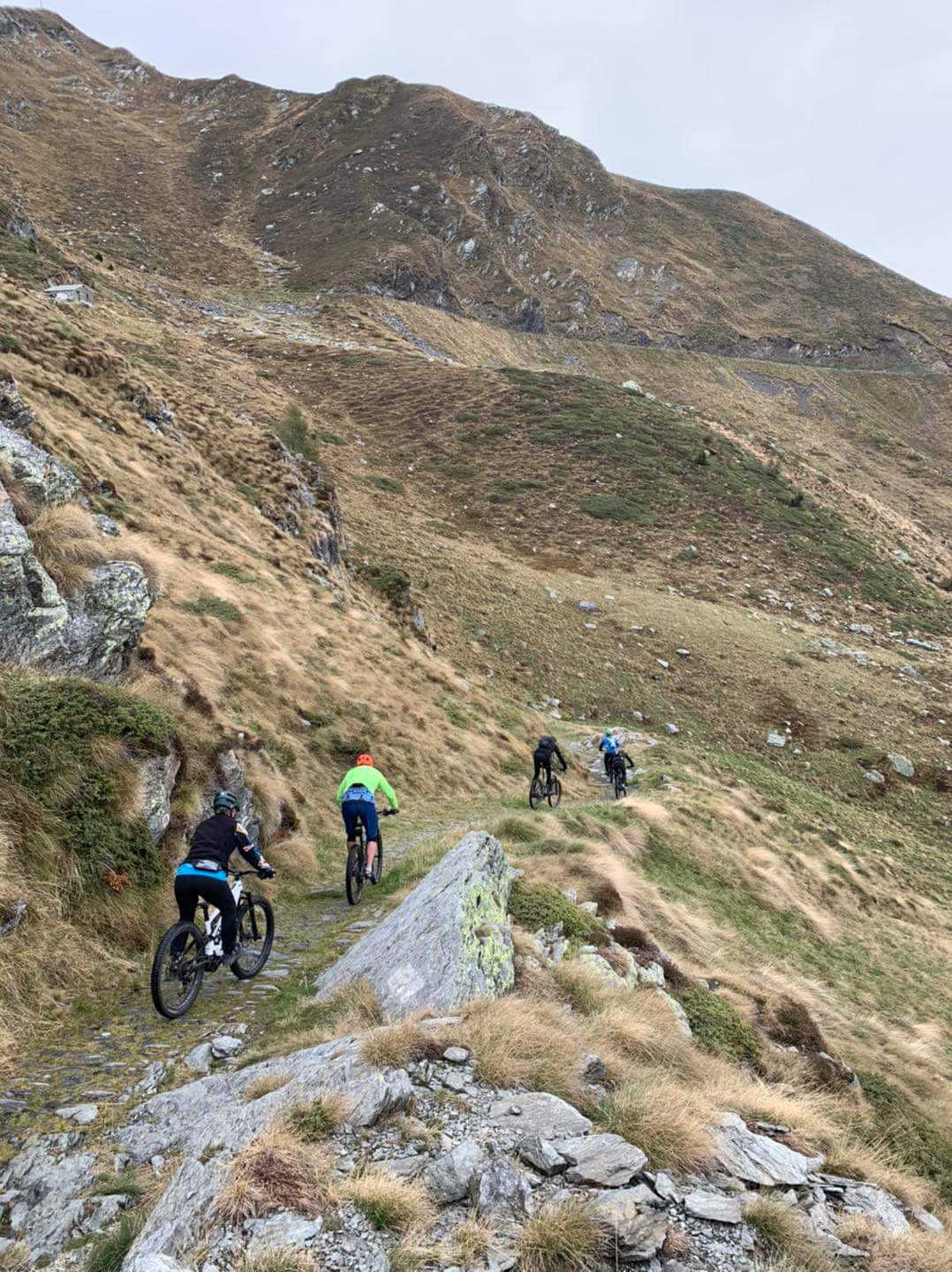 Fyra cyklister på rad i ett bergsparti på en stenig stig