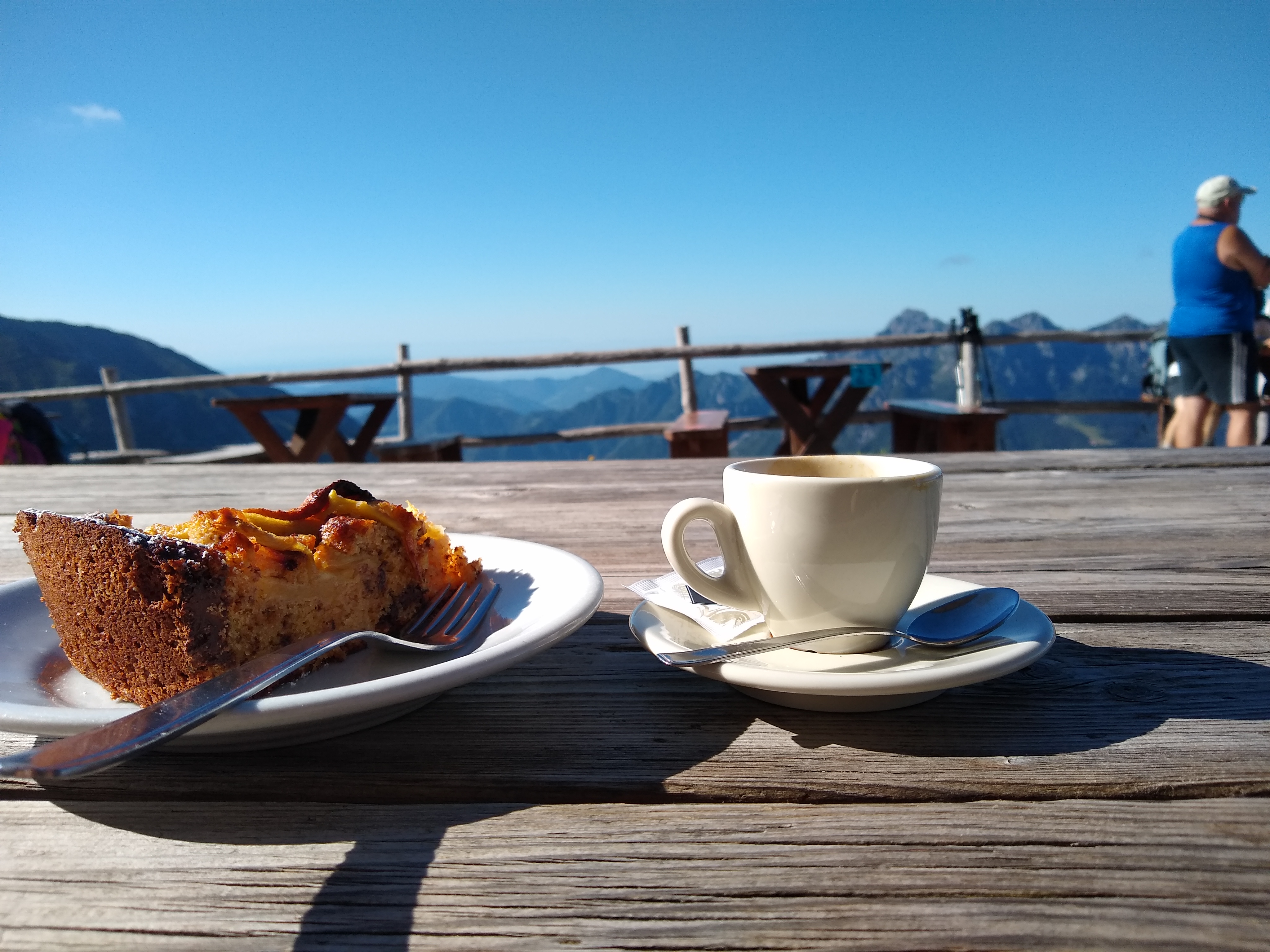 Kaffekopp och kaka på fat serverat på bord med utsikt över bergen